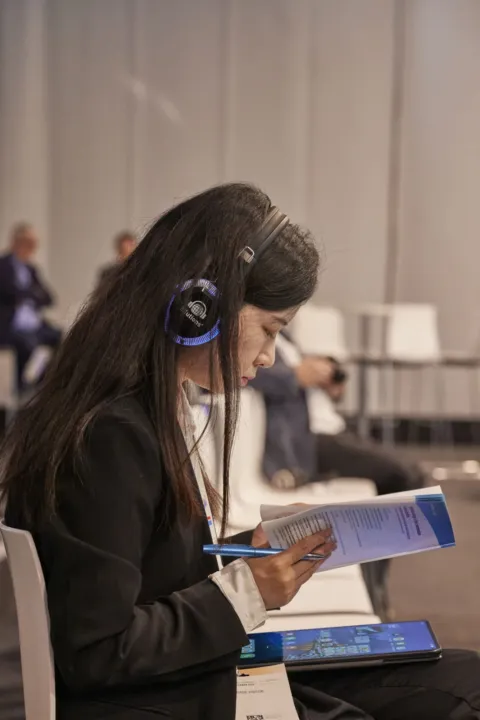 Participant with interpreting headphones reading the programme
