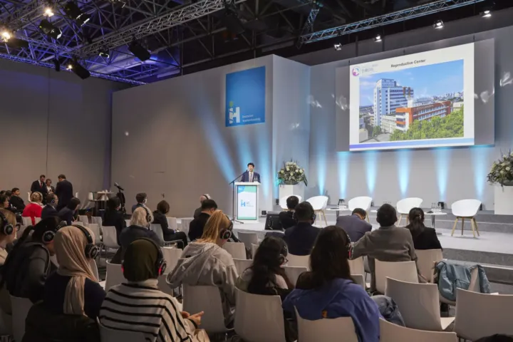Talk with a hospital photo on screen in front of a full hall