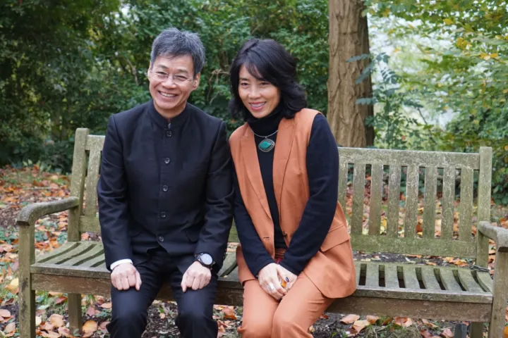 Two guests on a garden bench among autumn leaves